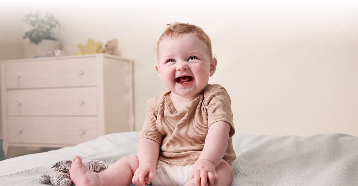A mother gently cradles her sleeping newborn, their cheeks touching in a tender embrace.