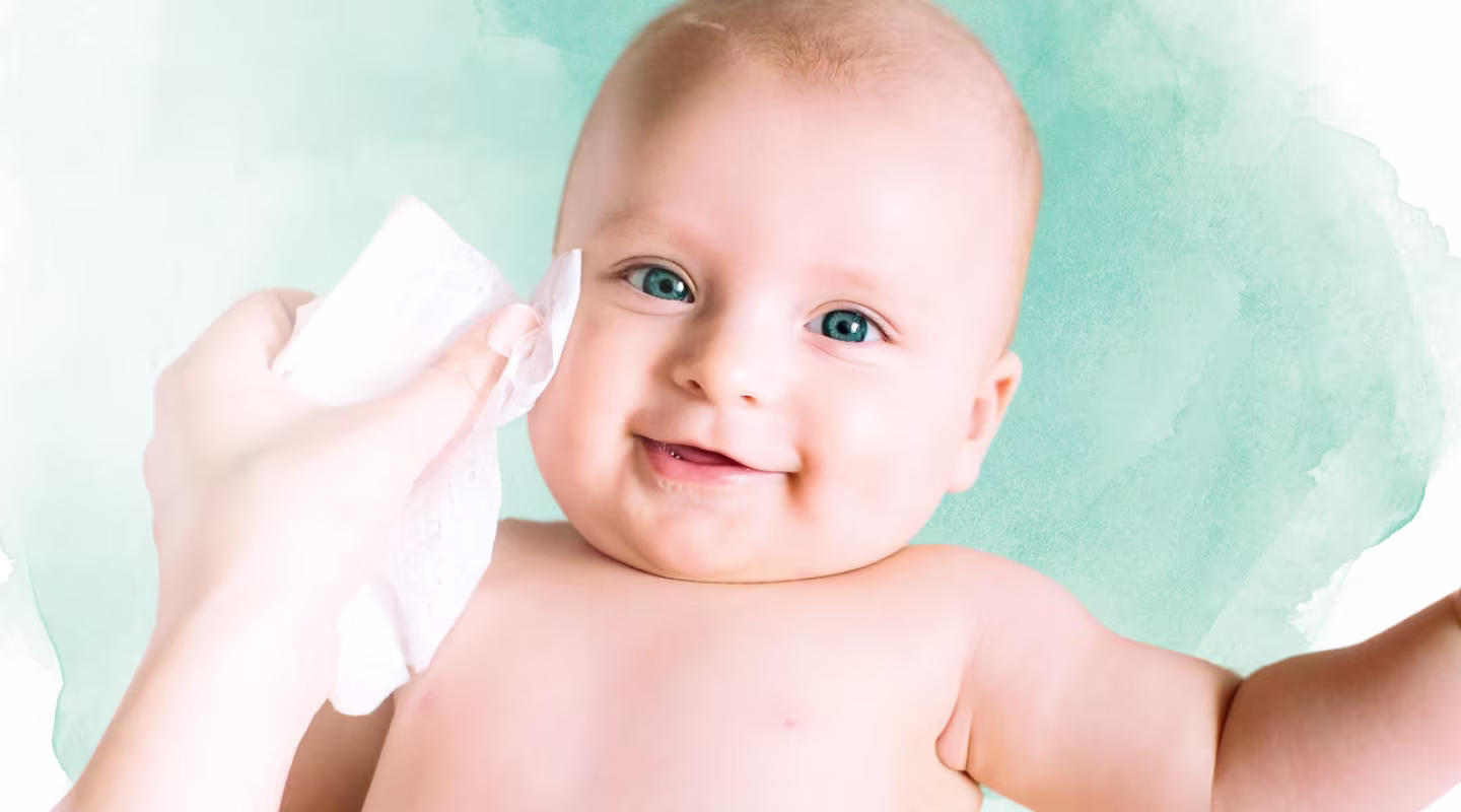 Un primer plano de la cara de un bebé mientras una mano le limpia suavemente la mejilla con una toallita Dodot Aqua Pure.
