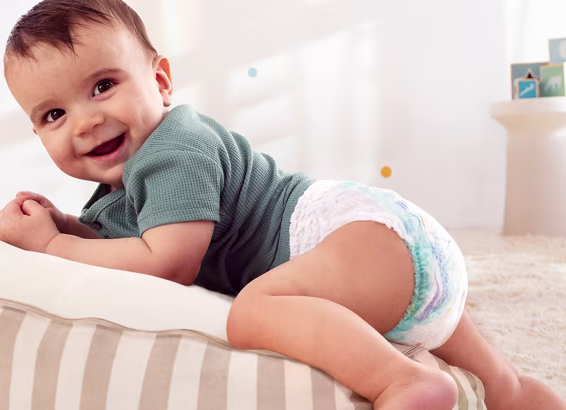 Ένα παιδί με πάνα Pampers μπουσουλάει πάνω σε ένα αφράτο μπλε χαλί