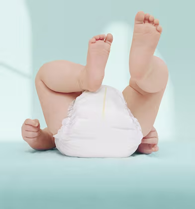 A baby lies on his back, showing his bottom covered by a white Pampers nappy A baby lies on his back, showing his bottom covered by a white Pampers nappy