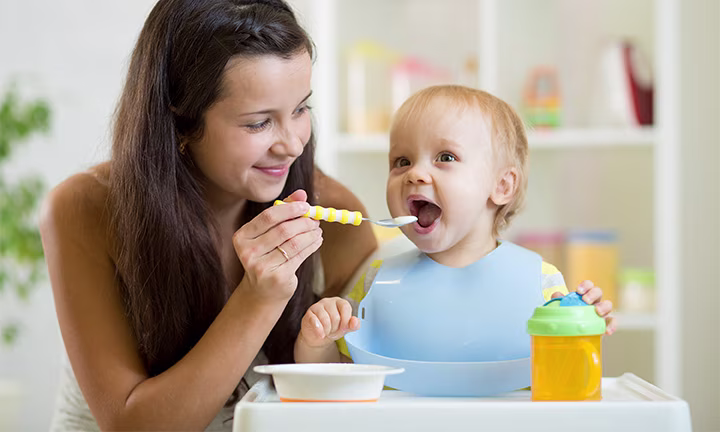 Eine Mutter füttert ihr Kleinkind mit Brei