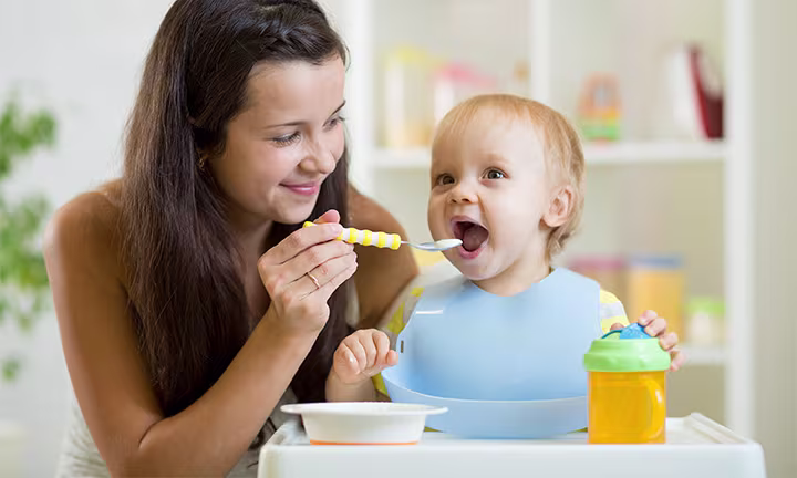 Eine Mutter füttert ihr Kleinkind mit Brei