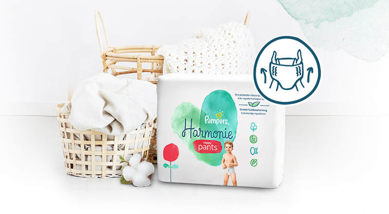 Interiorul unei camere cu decor în culori deschise în care se vede așezat pe o canapea pachetul de Pampers Harmonie Pants.