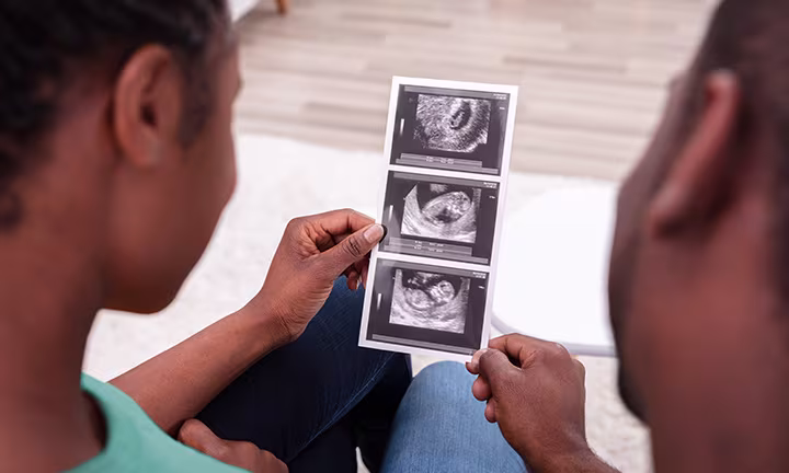 Couple looking at ultrasound images, sharing a moment of anticipation and joy.