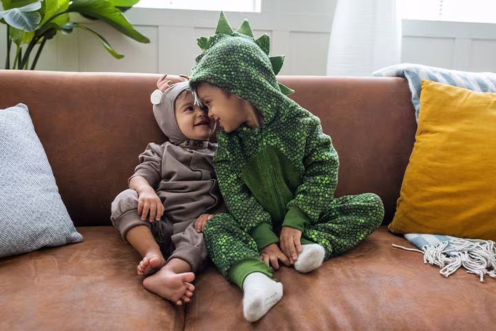 Μωρό και νήπιο στον καναπέ, ντυμένα με στολές ζωάκια