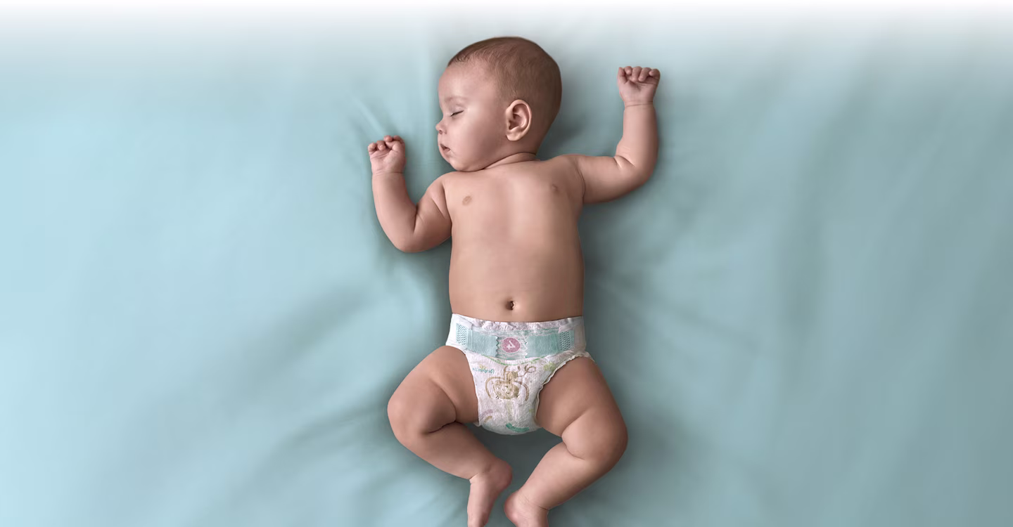 En baby sover lugnt i en vagga, insvept i en mjuk vit filt.