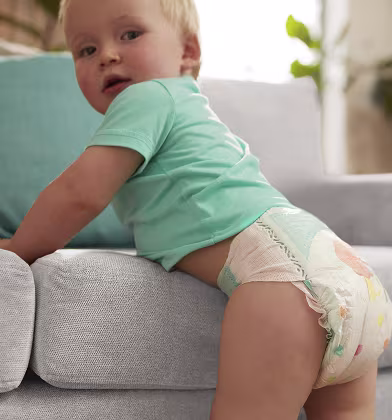 Zvědavé miminko v plence Pampers se dívá přes pravé rameno