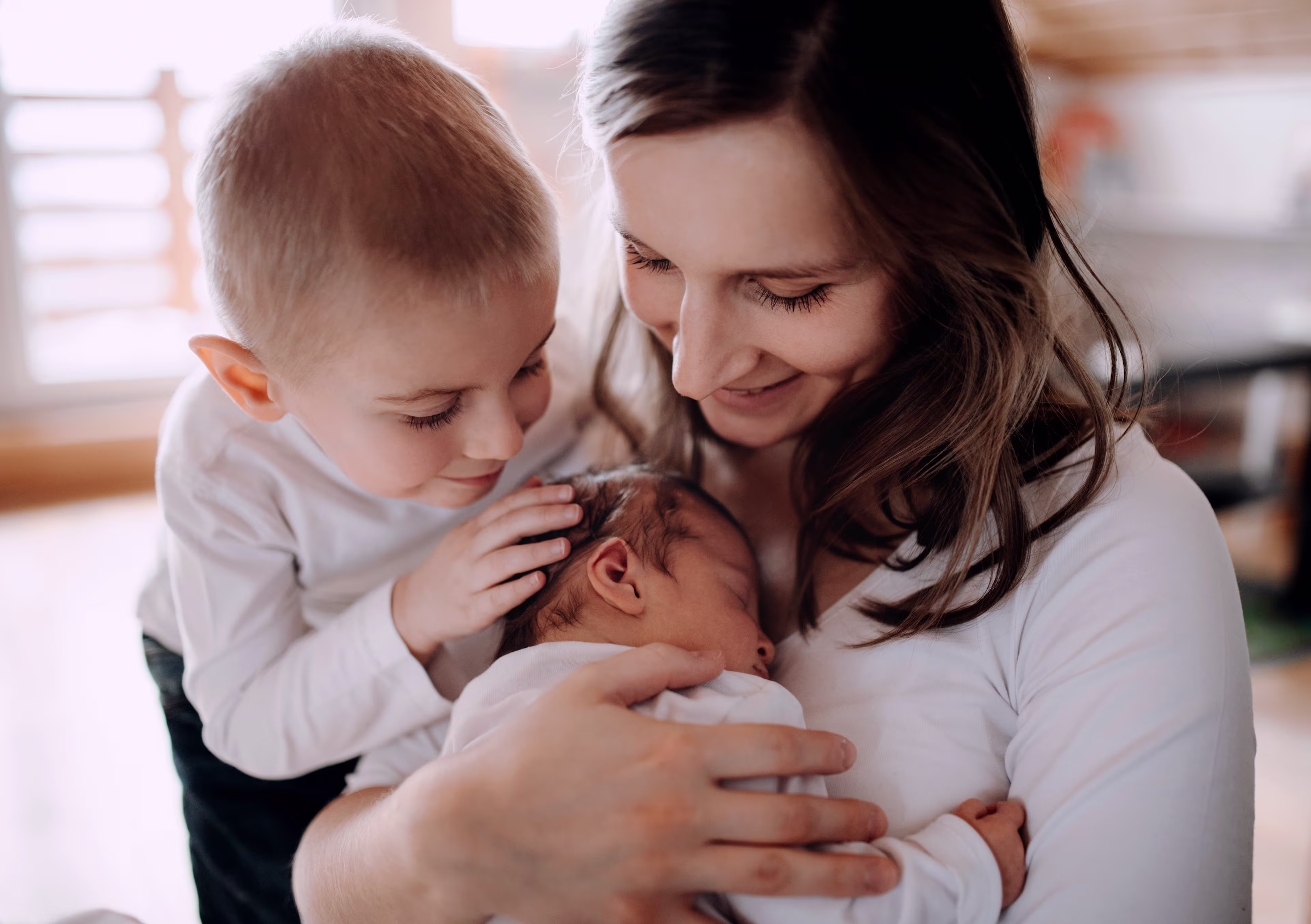 Mom and big brother admiring baby brother in mom's arms.