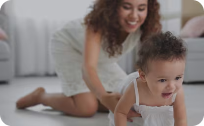 Happy baby crawling on floor with mom crawling behind