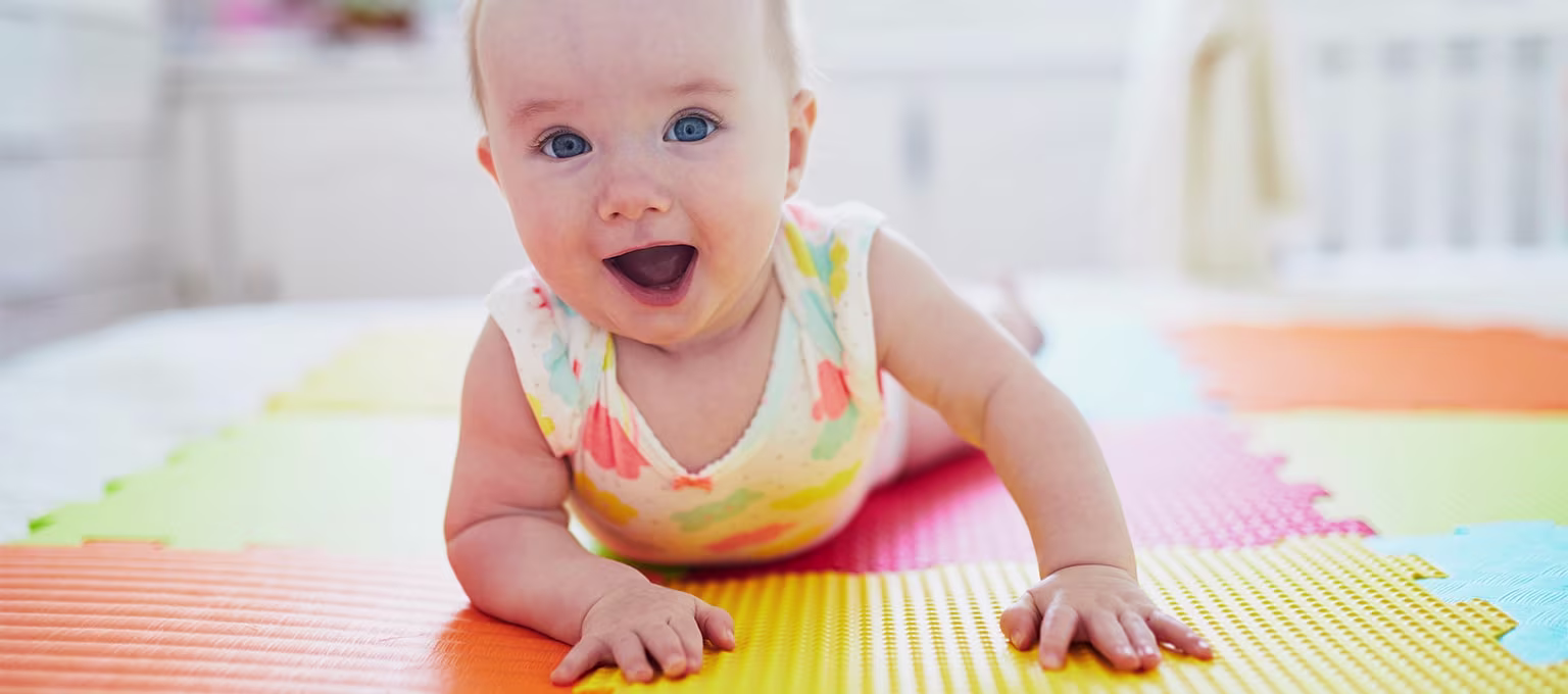Baby practicing tummy time on a soft pad to strengthen muscles and promote development