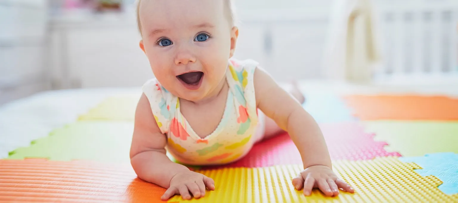 Baby practicing tummy time on a soft pad to strengthen muscles and promote development