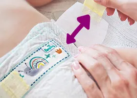 Δύο χέρια κρατούν την πάνα και το πλαϊνό αυτοκόλλητό της.