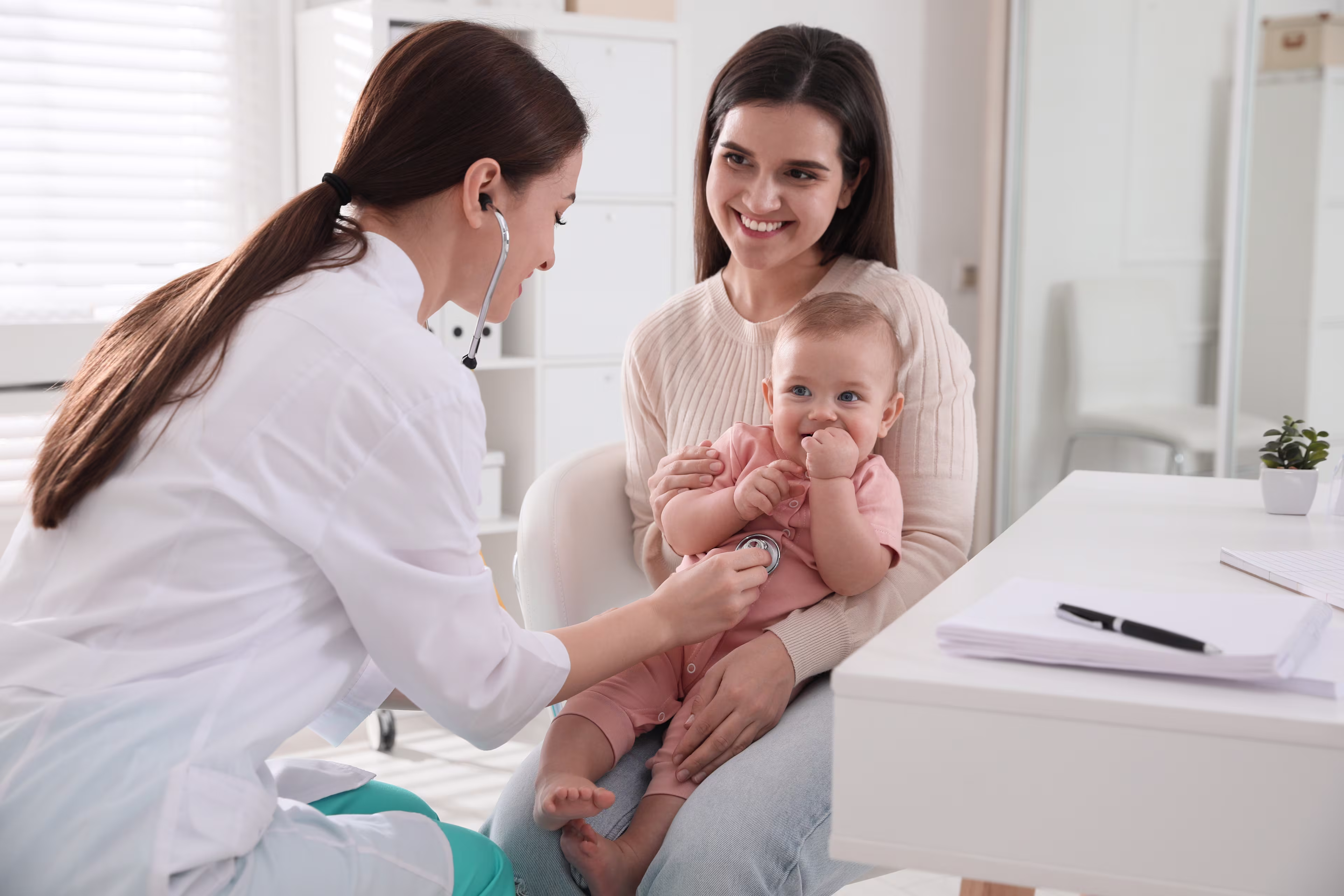 Pediatrician assessing a baby sitting in mom's lap.