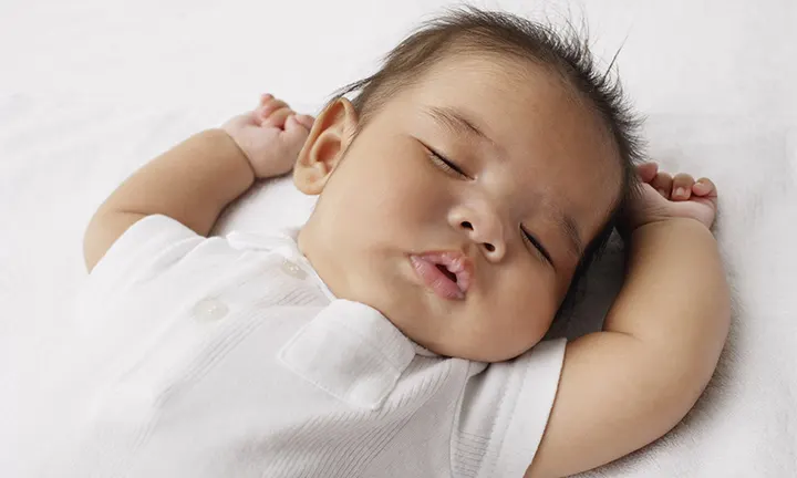 A baby soundly sleeping in a crib -  a quiet moment in their sleep cycle.