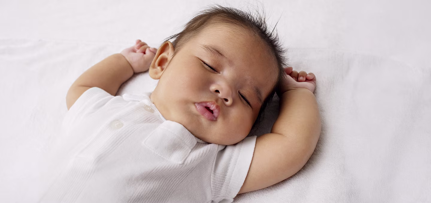 A baby soundly sleeping in a crib -  a quiet moment in their sleep cycle.