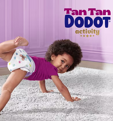 Un bebé en un suelo alfombrado en una habitación morada, vestido con un pañal blanco con coloridos diseños de animales de dibujos animados.