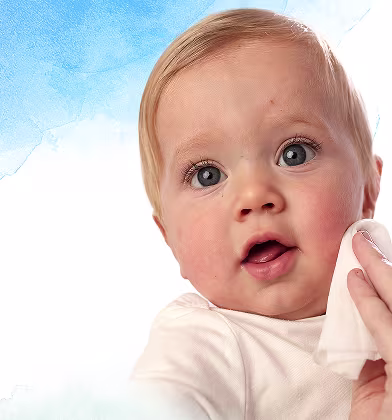 Un primer plano de la cara de un bebé mientras una mano le limpia suavemente la mejilla con una toallita Dodot Aqua Pure.