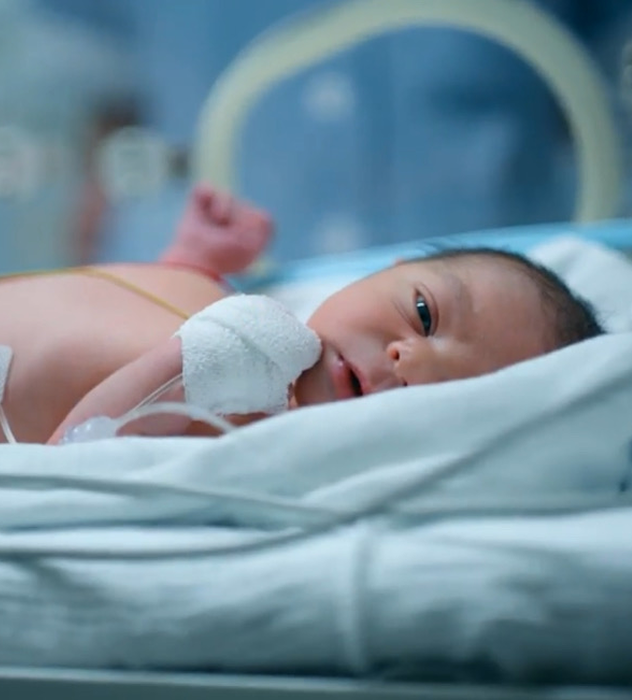 Image of a preemie baby in the NICU looking at the camera