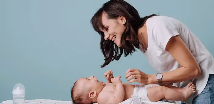 Mamá cambiando pañal a su hijo