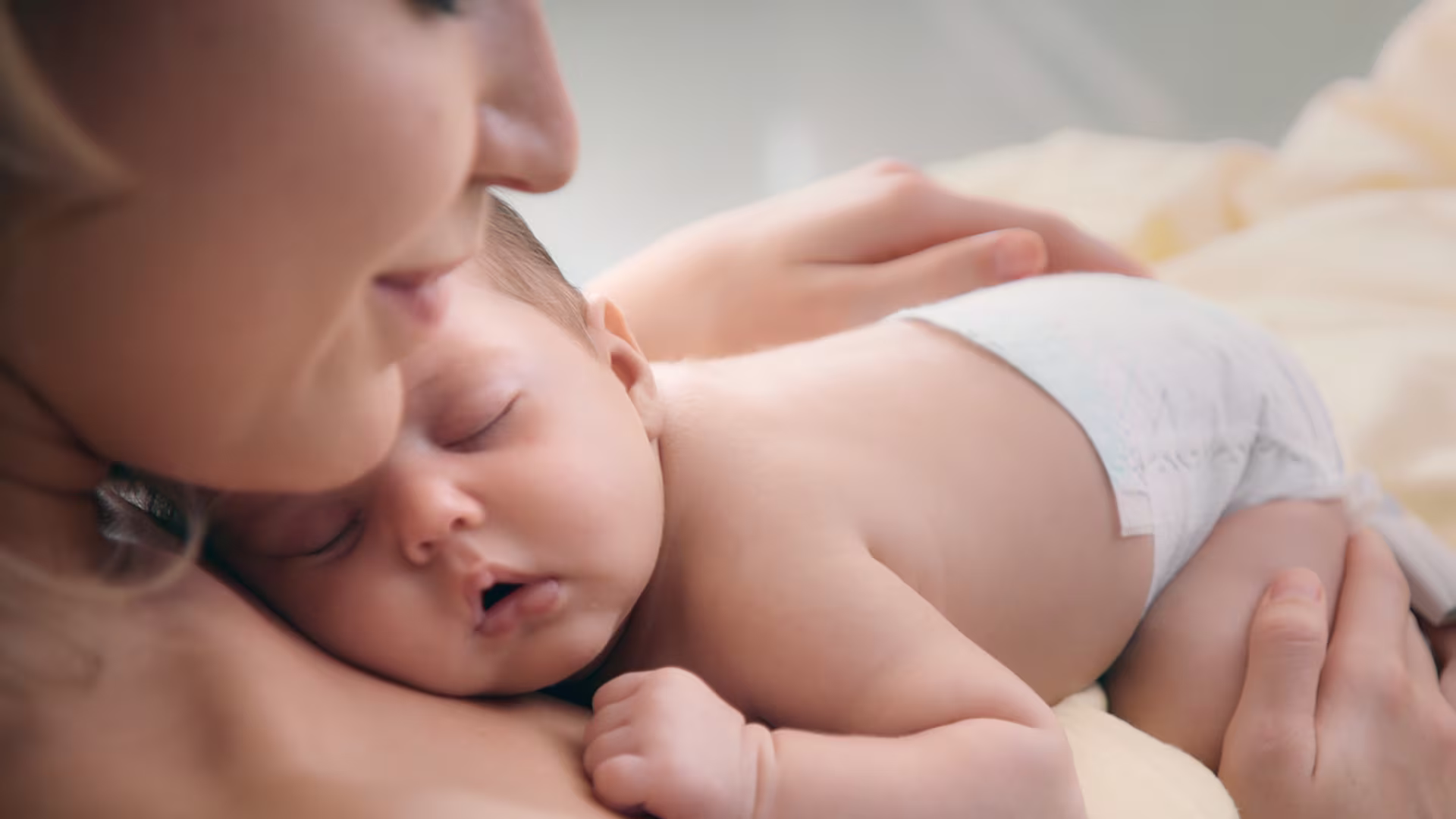 Nyugodt újszülött alszik édesanyja mellkasán, Pampers Premium Care pelenkát viselve