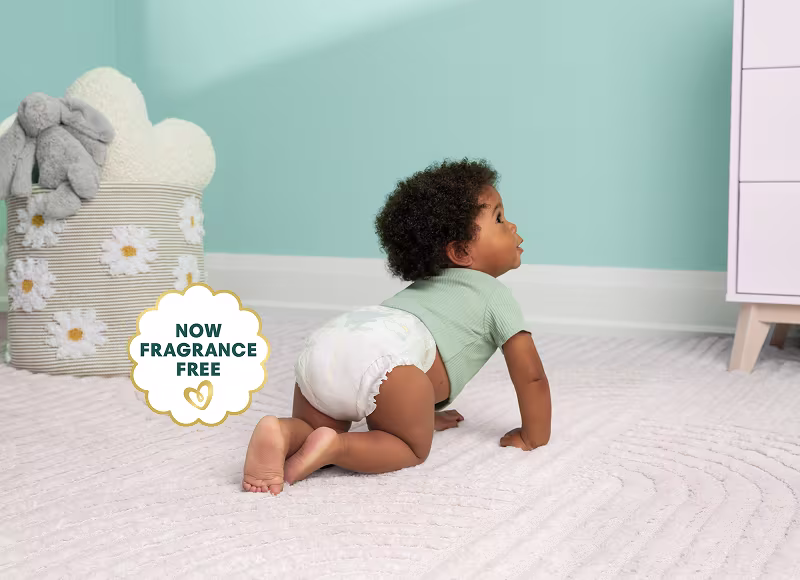 Baby crawling away on their nursery floor while wearing Pampers Swaddlers Ultra and a green shirt