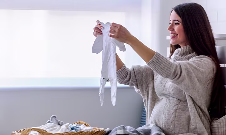 Woman holding up baby clothes