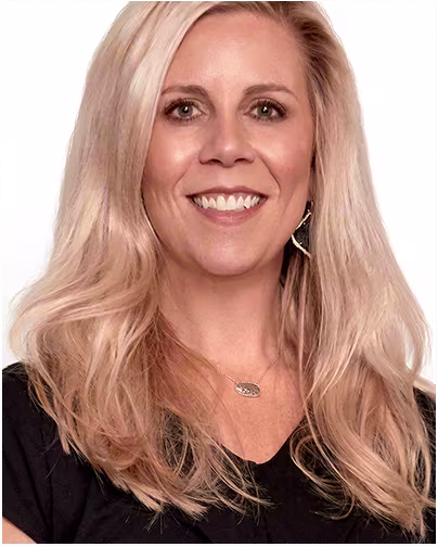 A female scientist with blonde hair and blue eyes and long wavy hair smiles.