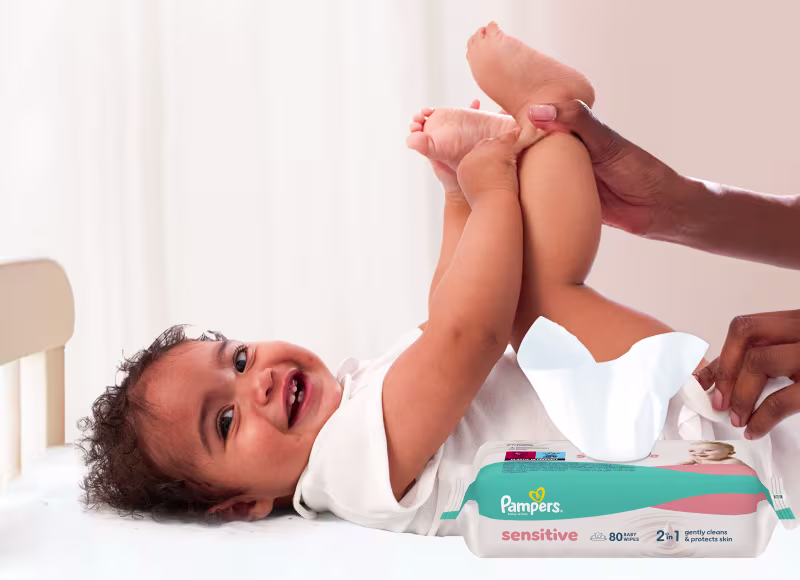 Baby liegt auf dem Rücken und wird sanft mit einem Feuchttuch gereinigt.