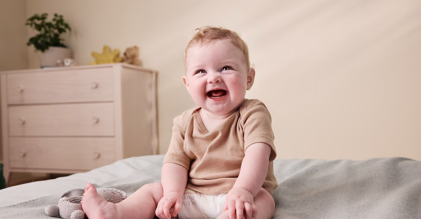 Bebé sonriendo sentado en una cama