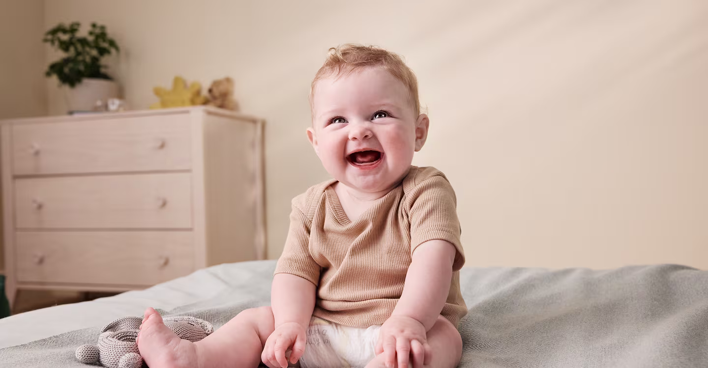 Bebé sonriendo sentado en una cama