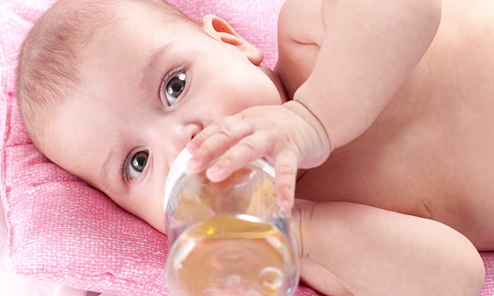 Baby trinkt Tee aus Babyflasche