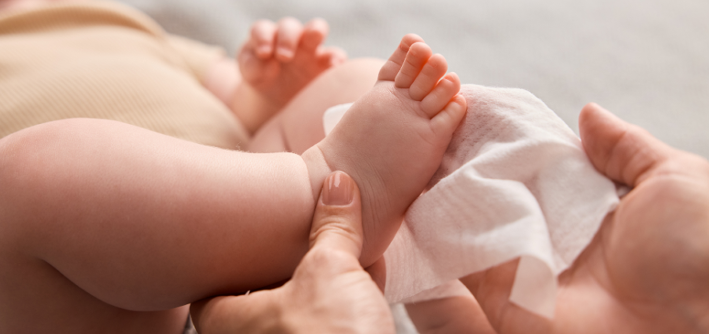 Close up of parent softly wiping baby’s foot with a baby wipe