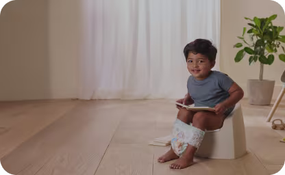 Pelenkás Pampers bugyiban ülő kisgyerek a bilín