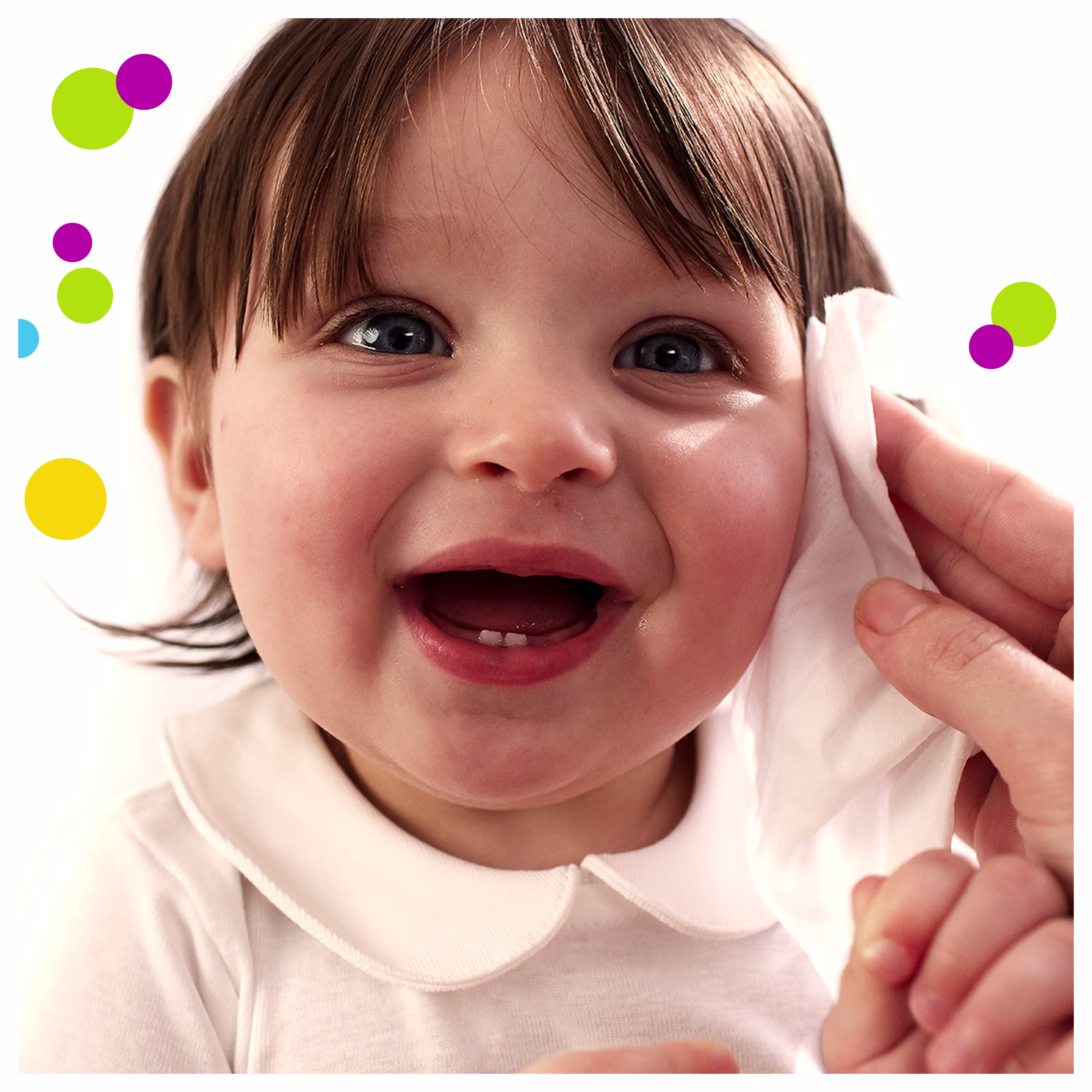 Imagine cu un bebeluș care zâmbește și o mână de adult îl șterge ușor pe obrăjor cu un șervețel.​