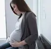 Epidural: A pregnant woman contemplates her belly on the table in the doctor’s office