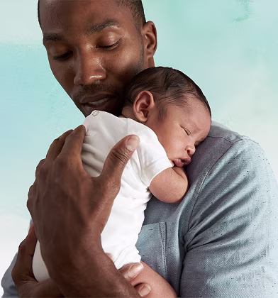 En far håller kärleksfullt sin sovande nyfödda baby på sin axel.