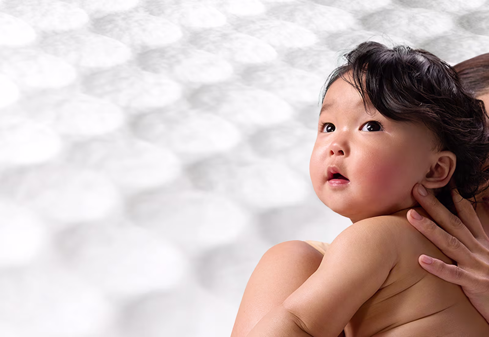 Uma mãe a segurar um bebé, com uma textura suave de toalhitas atrás