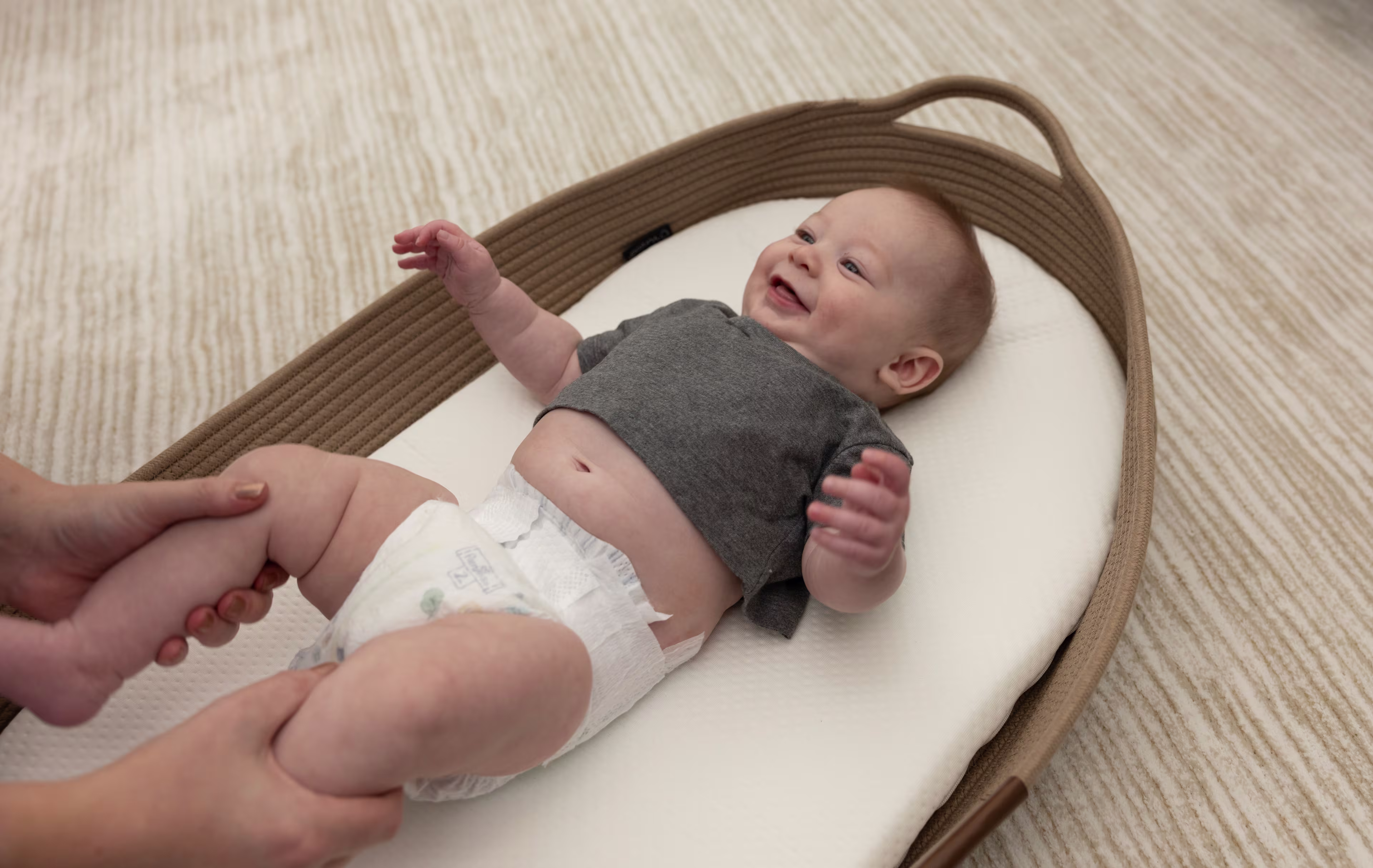 Baby smiling at their mom while laying in a basket