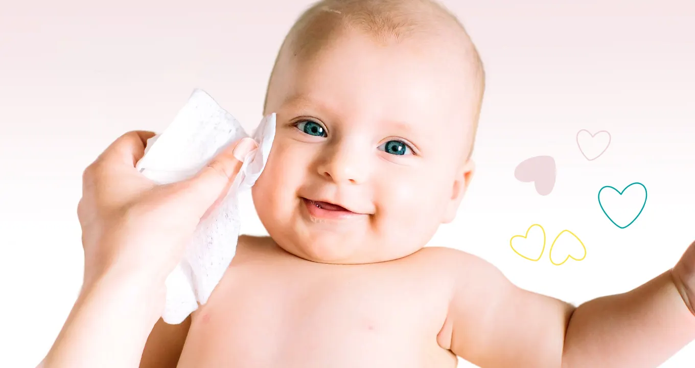 Lächelndes Baby das sanft mit Pampers Sensitive Feuchttüchern sauber gemacht wird