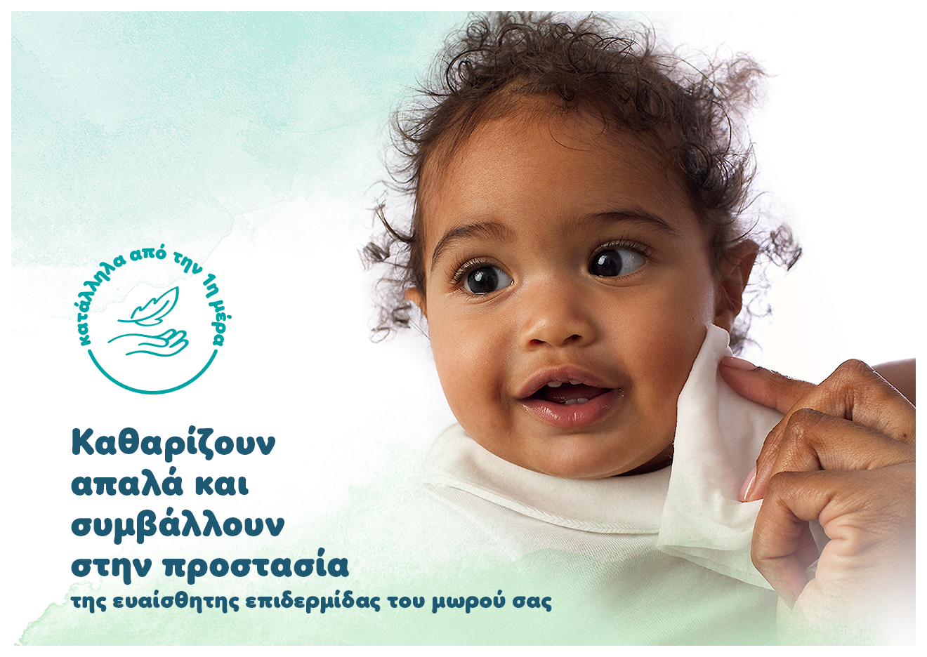 Σε ένα μωράκι ένα χέρι ακουμπάει ένα μωρομάντηλο στο αριστερό του μάγουλο. Αναγράφονται τα κείμενα: «Καθαρίζουν απαλά και συμβάλλουν στην προστασία της ευαίσθητης επιδερμίδας του μωρού σας και Κατάλληλα από την πρώτη μέρα».