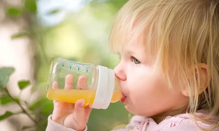 Banner image of a baby having fruit juice for the article -When Can Babies Have Fruit Juice?