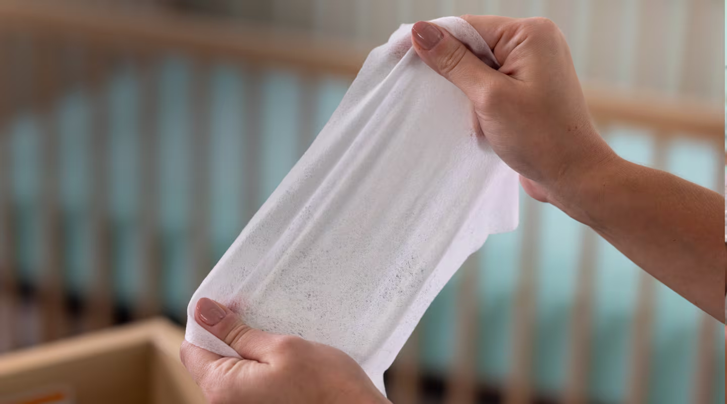 Acercamiento de dos manos jalando una toallita húmeda Complete Clean para mostrar lo resistente y suave que es.