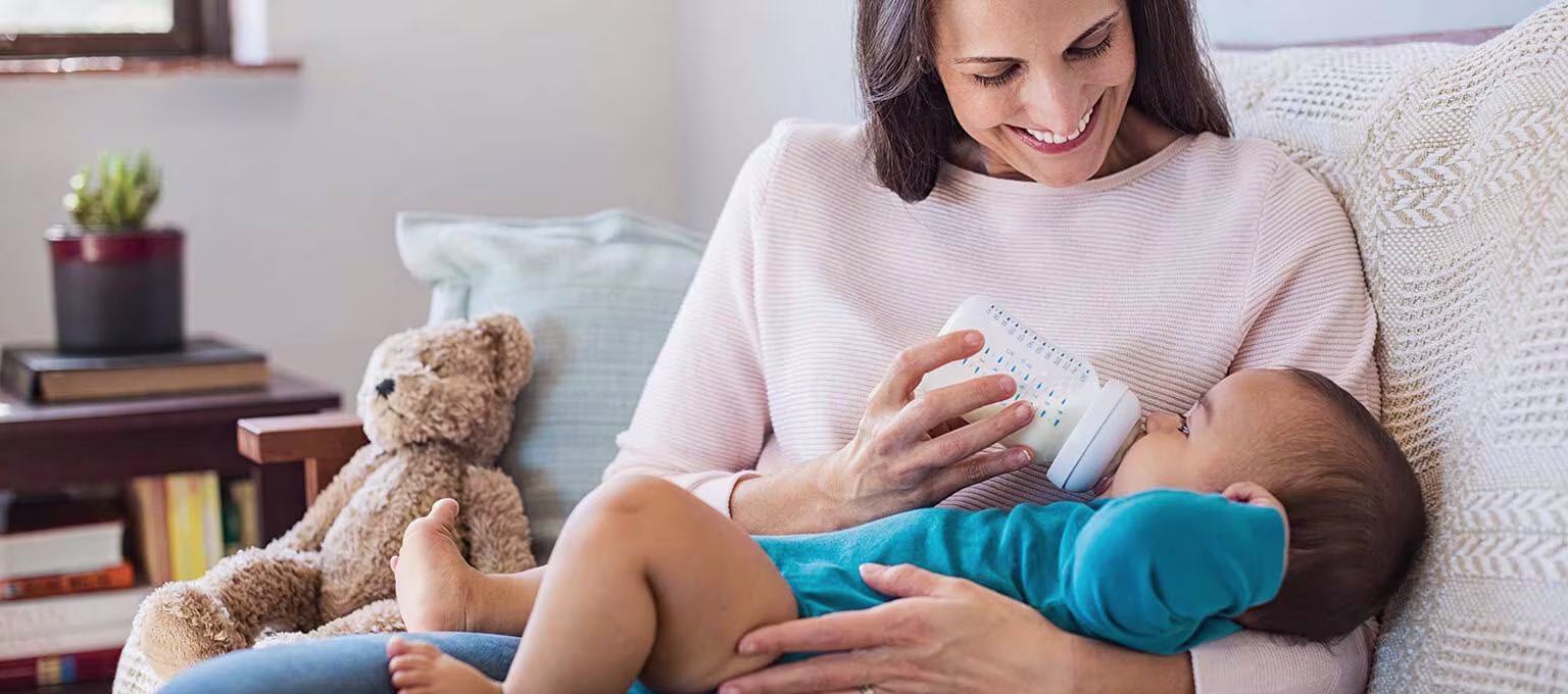 A mother feeding her baby with a bottle of formula.