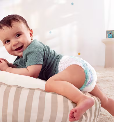 Um bebé que usa uma fralda-cuequinha Dodot rasteja sobre um suave tapete azul.