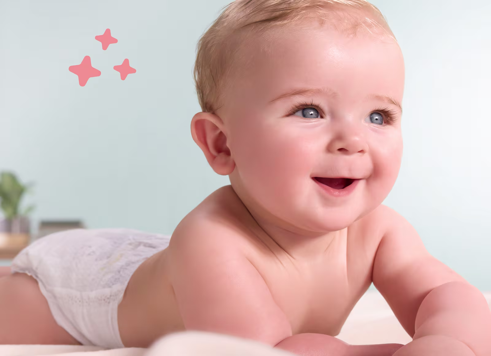 Een vrolijke baby met blauwe ogen, liggend op zijn buik en glimlachend, terwijl hij naar boven en opzij kijkt.