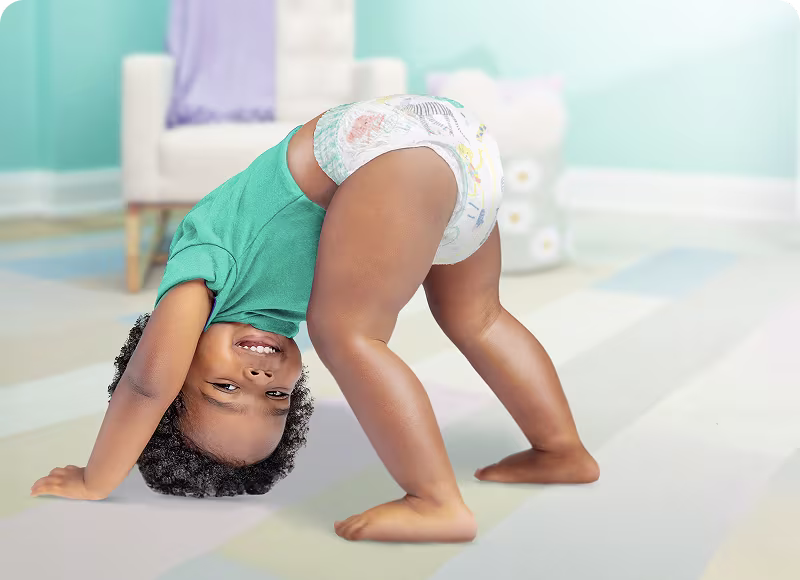 Toddler playing doing downwards dog yoga pose wearing Pampers Cruisers360    