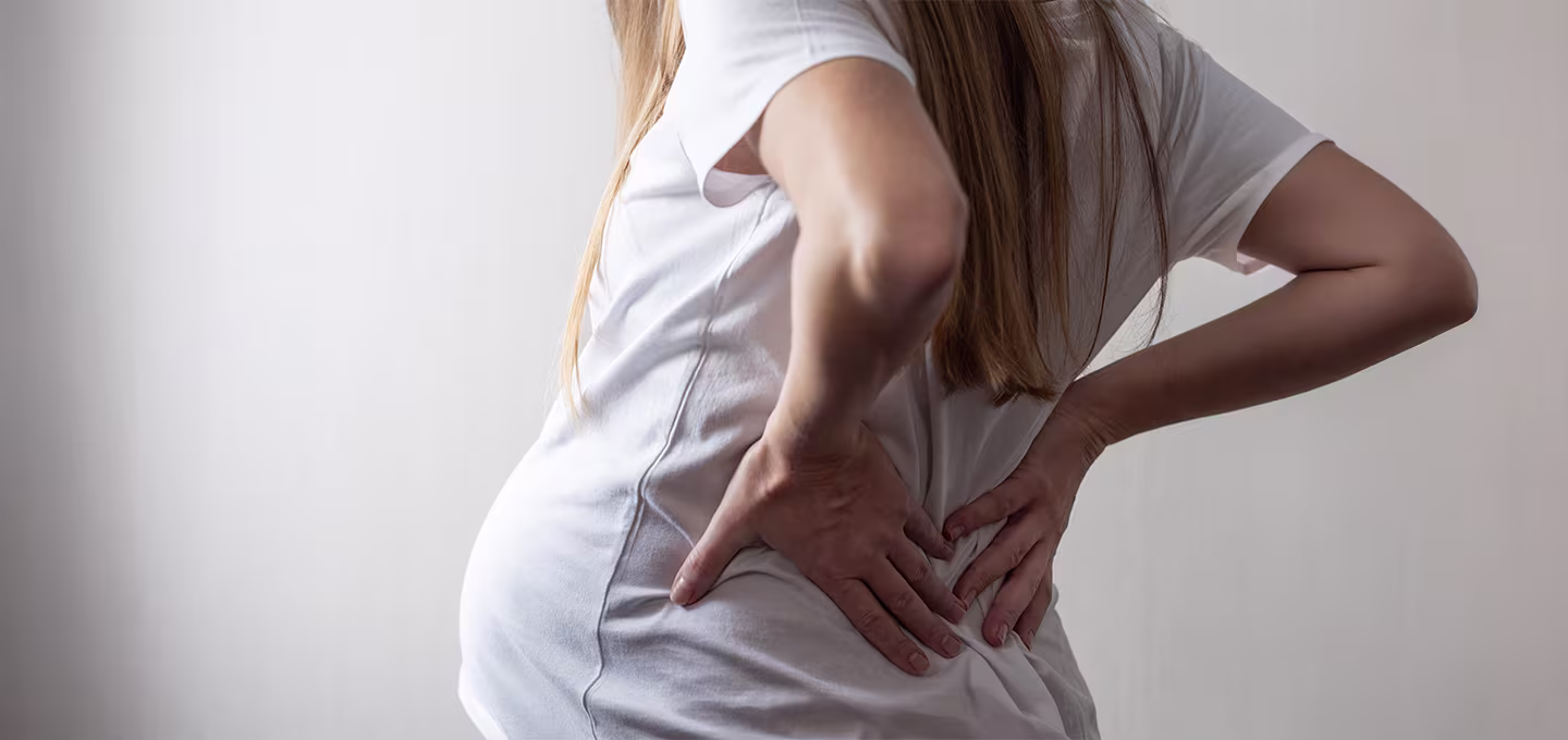 Pregnant woman holding her lower back, illustrating discomfort during pregnancy