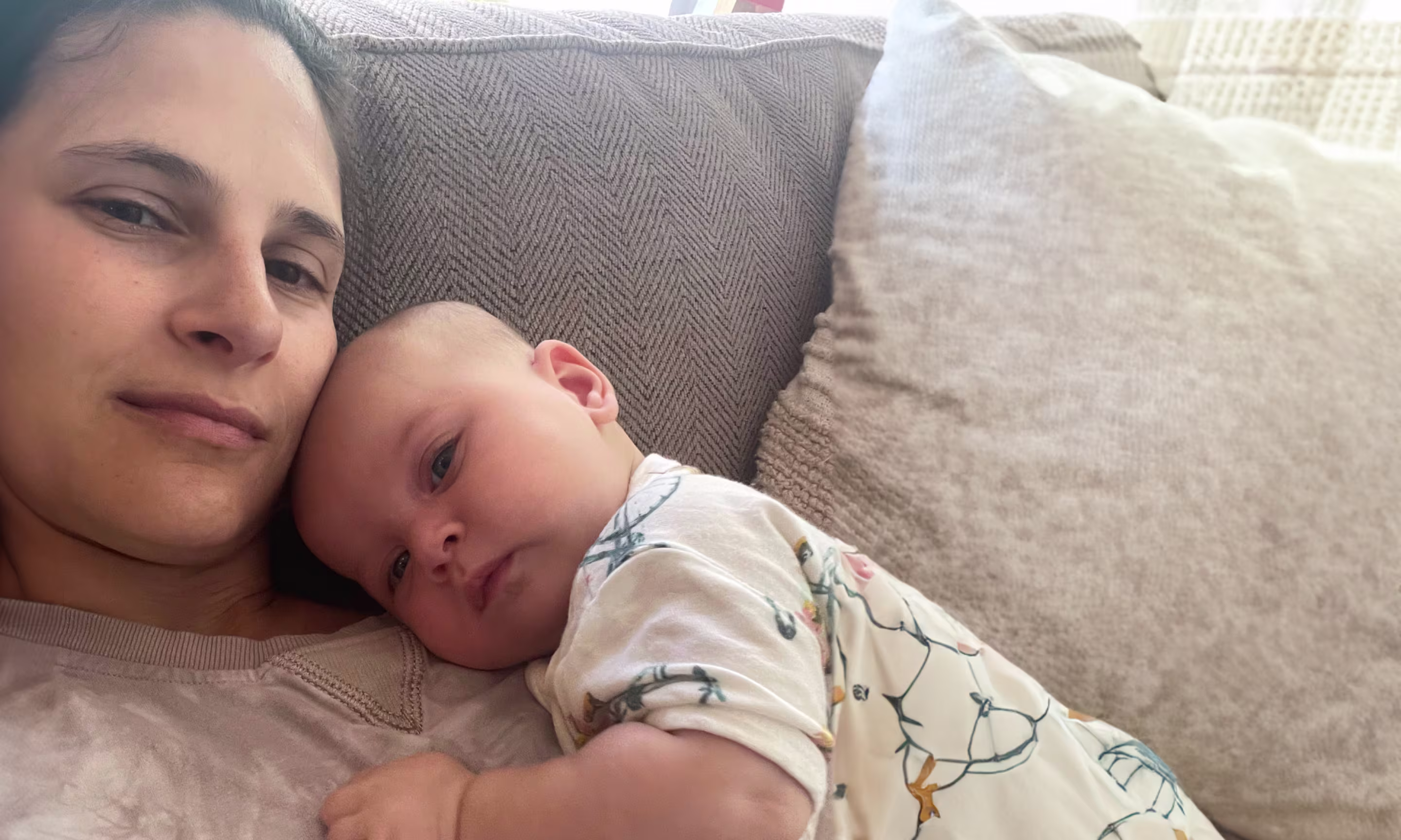 Mother and baby cuddling on a cozy sofa, conveying warmth and comfort.