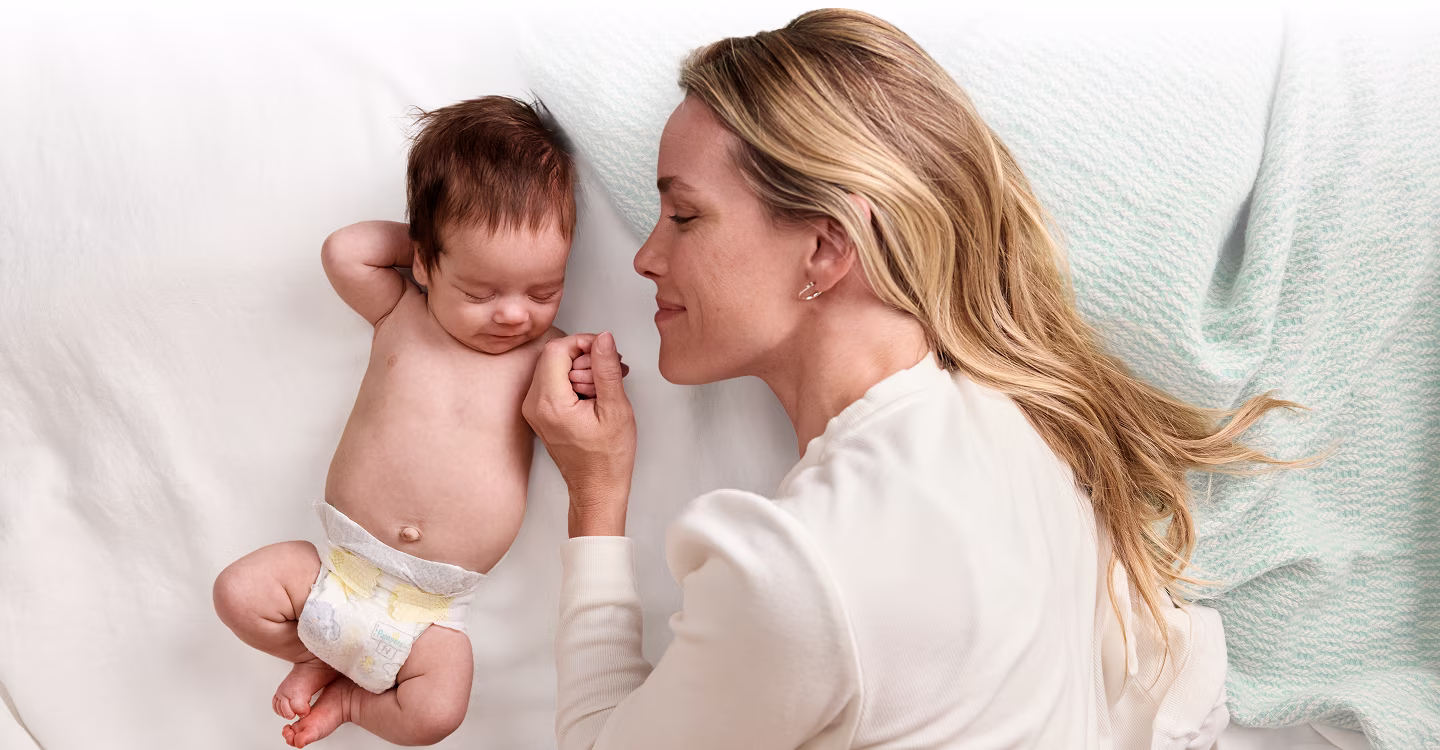 Mom laying with baby wearing a Pampers nappy