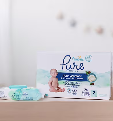 A box of Pampers Pure diapers sitting on a changing table alongside a pack of Pampers Aqua Pure wipes